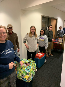 Students stand with donated foods in blue carts.