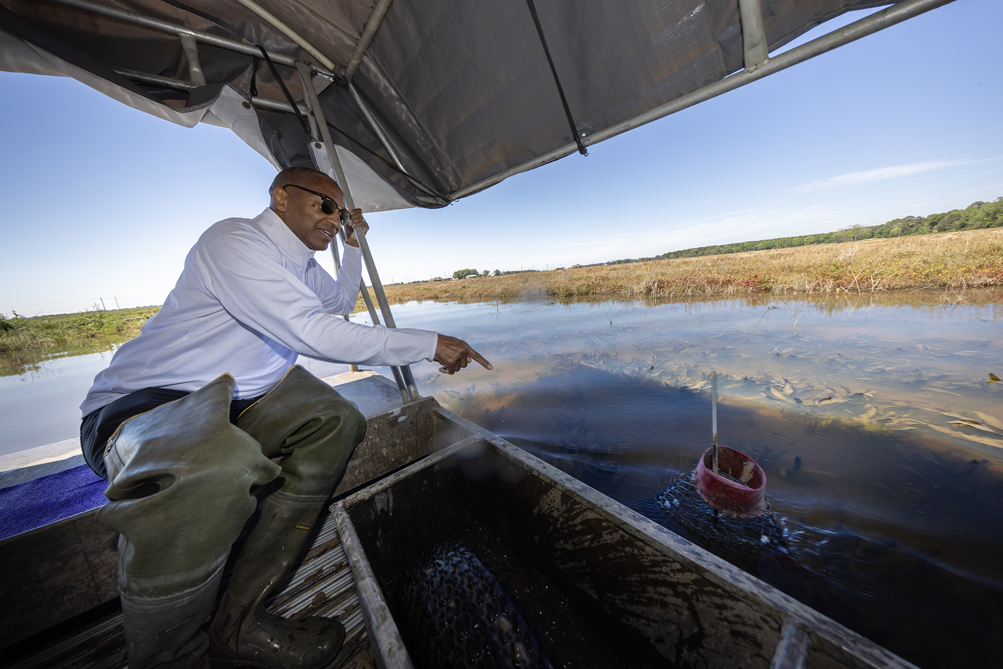 President Tate in a boat pointing at a crawfish trap