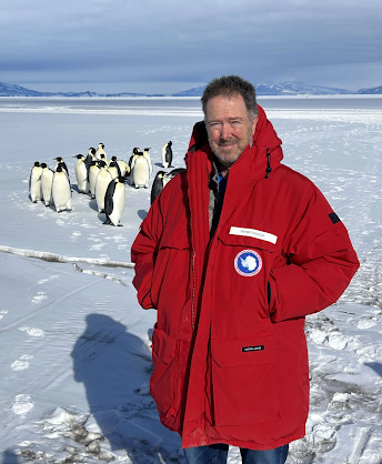 Peter Doran in frozen landscape with penguins in the background