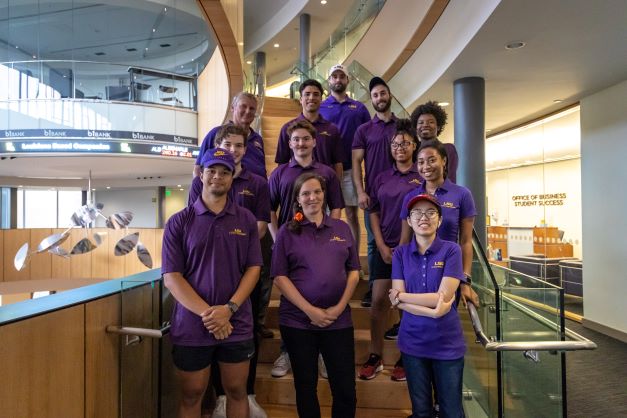 Group of people in purple polos on a staircase in the BEC