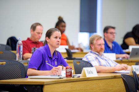 students in lecture hall listen and take notes in class. 