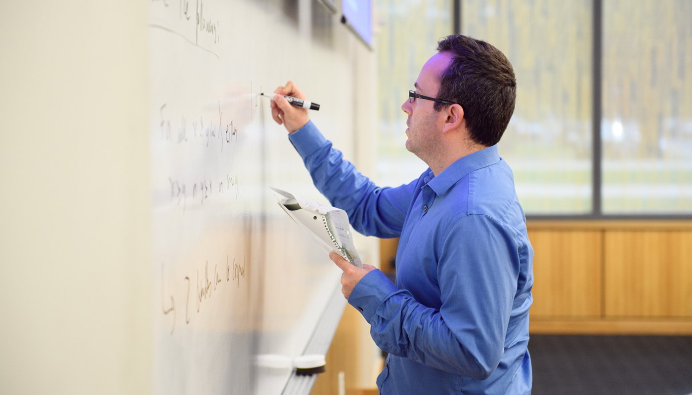 Man writes on white board.