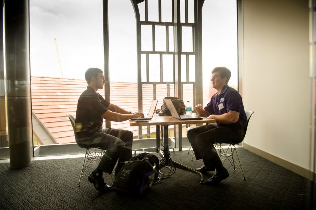 Two male students sitting at a table talking