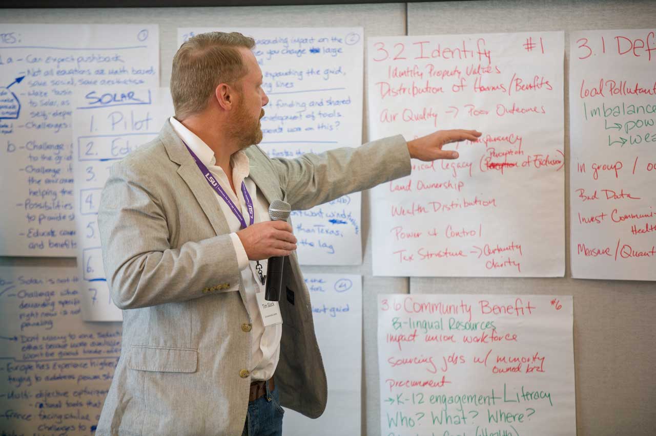 Man holding a microphone pointing at a wall of handwritten notes