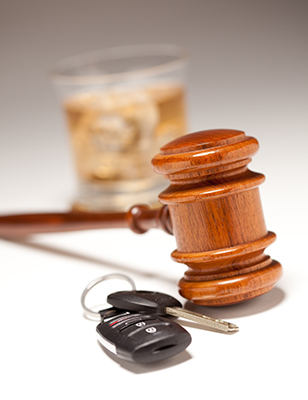 Photo of car keys in front of a gavel with a cocktail glass behind the gavel.